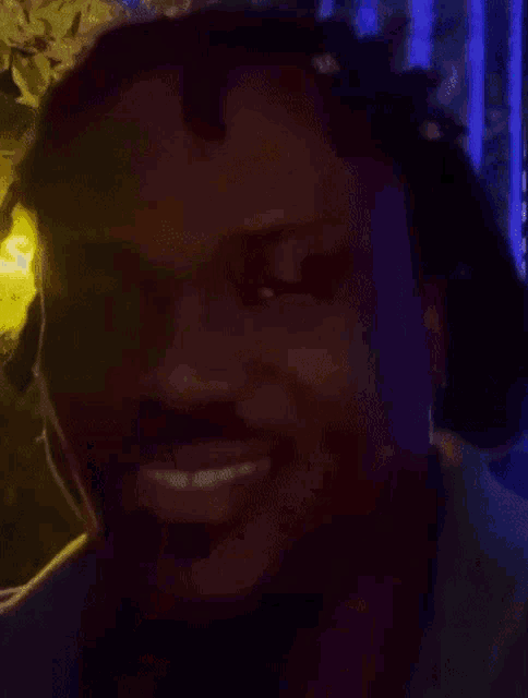 a close up of a man 's face with dreadlocks and a beard in a dark room .