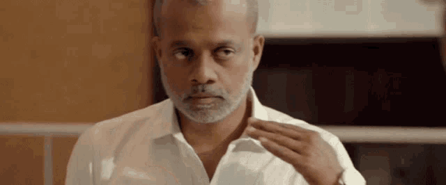a man with a beard is adjusting his shirt