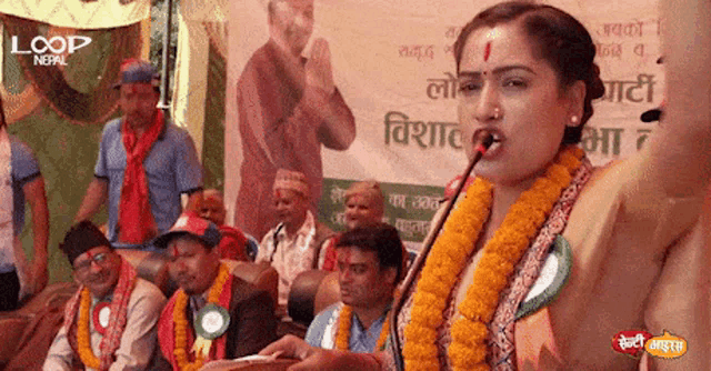 a woman is speaking into a microphone in front of a banner that says loop nepal