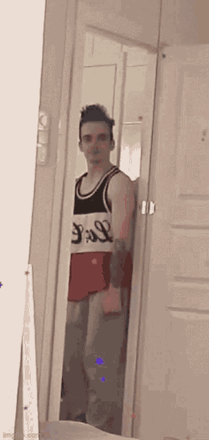 a man is standing in front of a mirror wearing a tank top that says ' s.s.l. ' on it