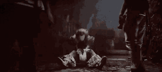 a person is kneeling down in a dark room with a flashlight in their hand .