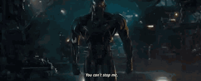 a man in a suit is standing in a dark room and talking to another man .