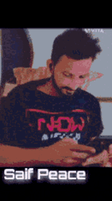 a man with a beard wearing a t-shirt that says " now "