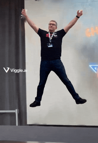 a man in a black shirt is jumping in the air with his arms outstretched in front of a sign that says viggle.ai