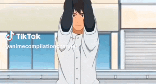a man in a white shirt is standing in front of a building with his hands behind his head .