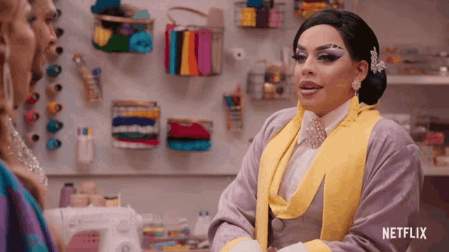 a drag queen is talking to a woman in front of a sewing machine with netflix written on the bottom