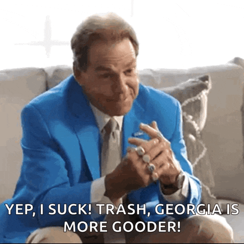 a man in a blue suit is sitting on a couch and says yep i suck ! trash georgia is more gooder