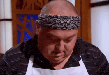 a man wearing an apron and a headband looks down