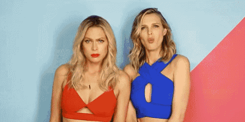 two women are standing next to each other in front of a blue and pink wall .