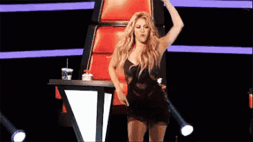 a woman is dancing on a stage in front of a red chair