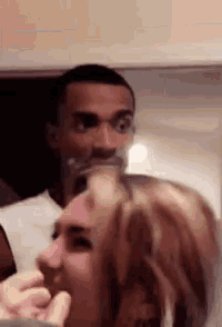 a man is holding a glass in front of a woman 's head .