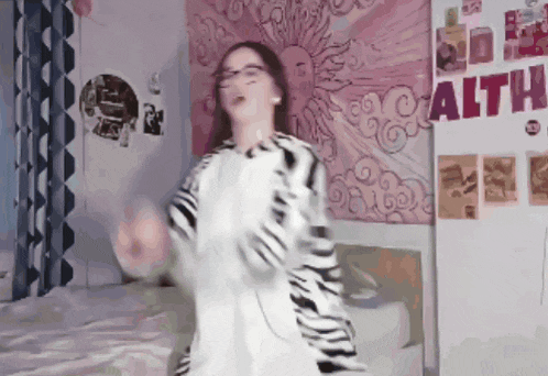 a girl is dancing in front of a wall that says " altho "