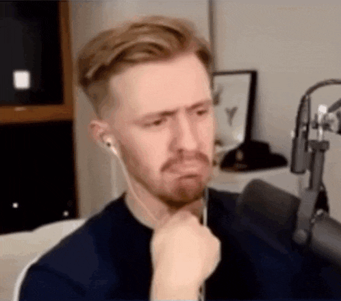 a man with a beard and headphones is sitting in front of a microphone and making a funny face .