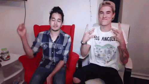 a man wearing a los angeles shirt is sitting next to another man in a red chair
