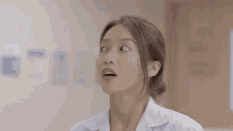 a woman in a white lab coat is standing in a room and looking up .