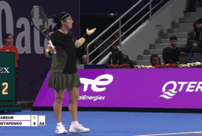 a woman holding a tennis racquet stands in front of a scoreboard with the number 2 on it