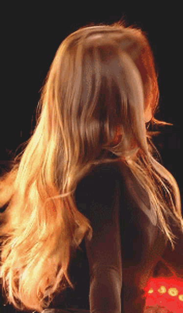 a woman with long blonde hair is standing in front of a red light