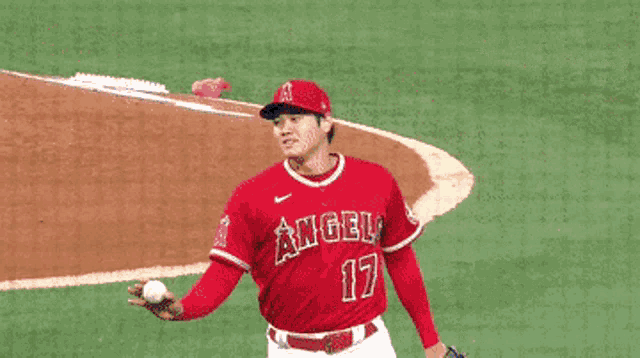 a baseball player wearing a red angels jersey is shaking hands with another player