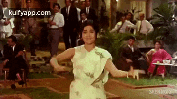 a woman in a white dress is dancing in front of a group of people .