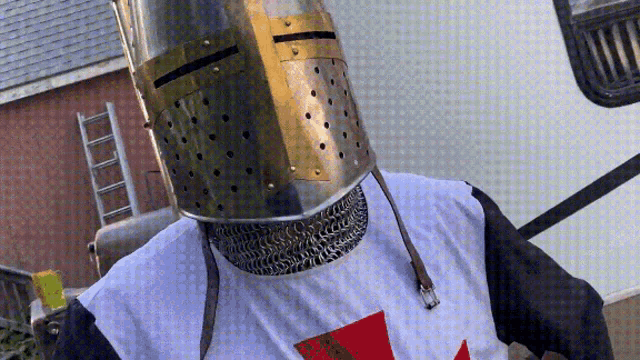 a man wearing a knight 's helmet and a white shirt with a cross on it