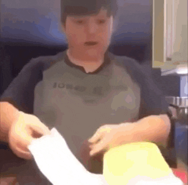 a young boy is holding a roll of toilet paper in his hands in a kitchen .