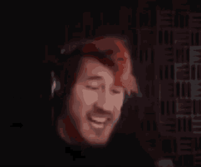 a man wearing headphones and a red hat is smiling in a dark room .