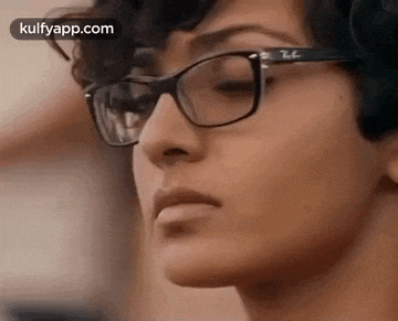 a close up of a woman wearing glasses and looking at the camera .