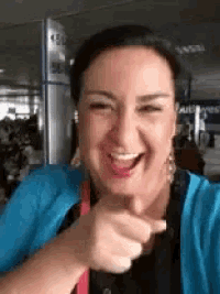 a woman in a blue cardigan is smiling and pointing