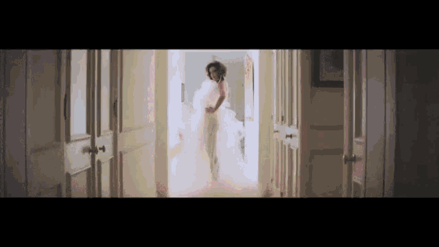 a woman in a white dress is running through a hallway