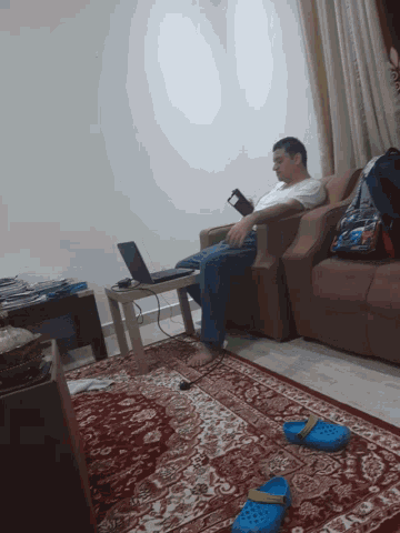 a man sits on a couch in a living room with his feet crossed