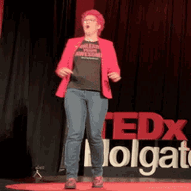 a woman with pink hair is standing in front of a sign that says tedx