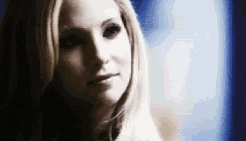 a close up of a woman 's face in a dark room with a blue background .