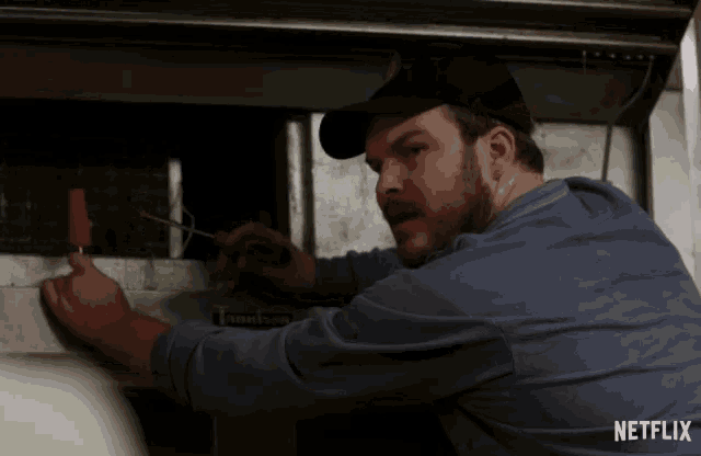 a man holding a screwdriver in front of a sign that says netflix on it