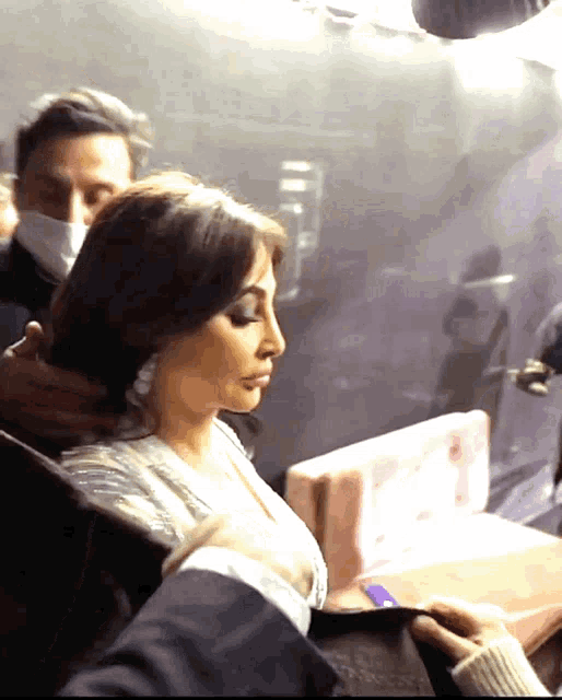 a woman wearing a mask is being helped by a man in a suit