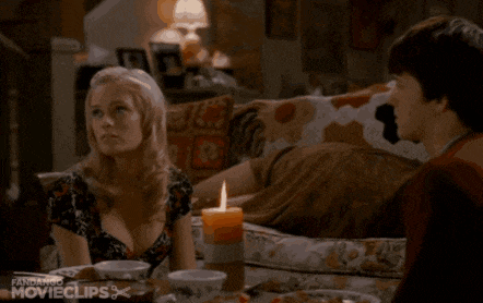 a man and a woman are sitting on a couch with a flame coming out of a candle