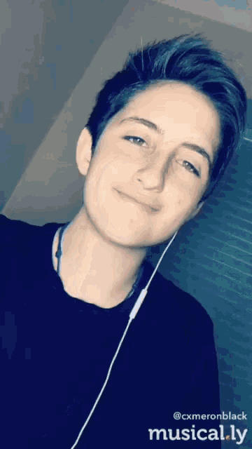 a young man wearing headphones and a black shirt is smiling for the camera