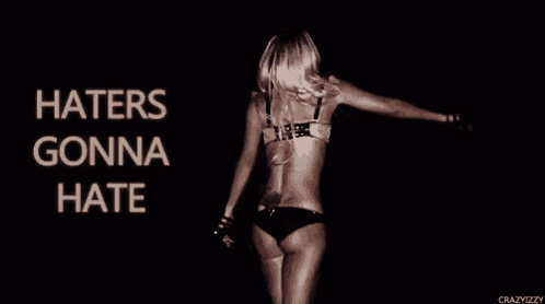 a woman in a bikini is dancing in front of a sign that says haters gonna hate