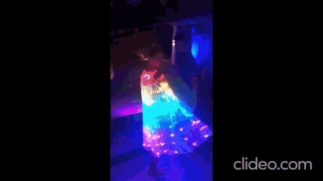 a girl in a dress is dancing in a dark room with a lot of lights .