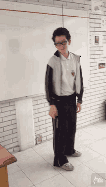 a boy wearing glasses is standing in front of a white board that says tik tok on it
