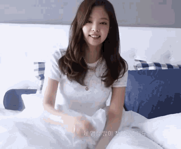 a woman in a white shirt is laying on a bed with a blue pillow