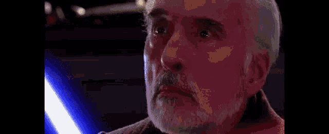 a man with a beard is holding a light saber in front of a blue light .