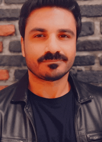 a man with a beard is wearing a black shirt and a black leather jacket