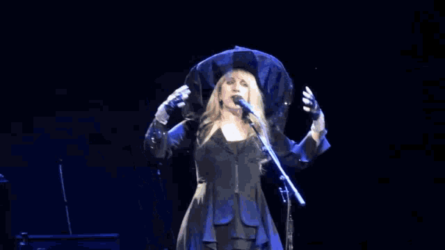 a woman singing into a microphone while wearing a witch hat