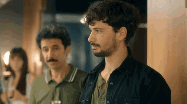 two men are standing next to each other in a room
