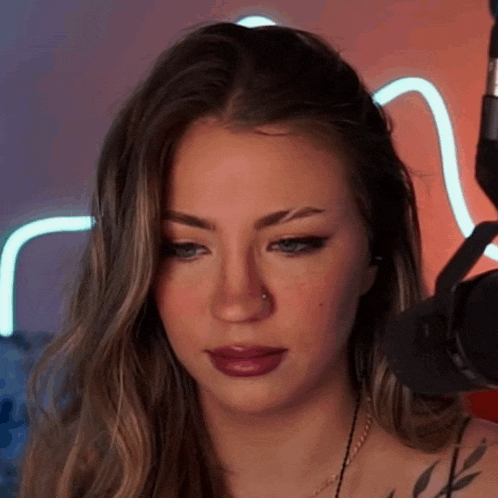 a woman with a nose ring is sitting in front of a microphone and making a funny face .