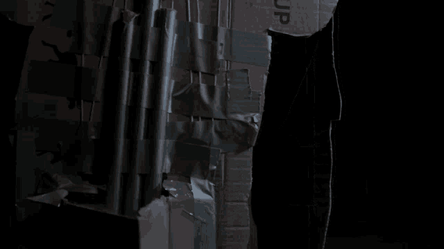 a person 's arm is taped to a cardboard box which says jp on it