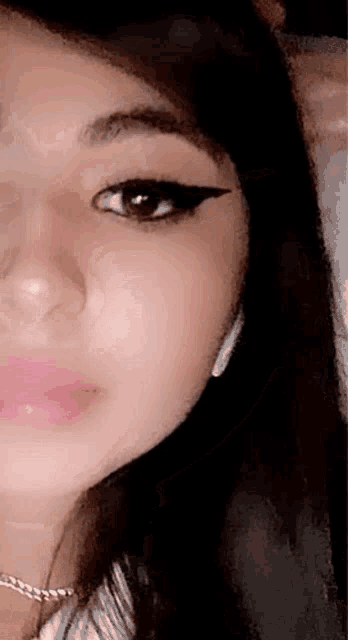 a close up of a woman 's face with a necklace and eyeliner .