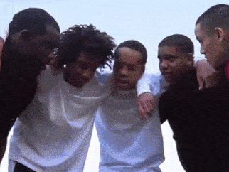 a group of young men standing in a circle with their arms around each other