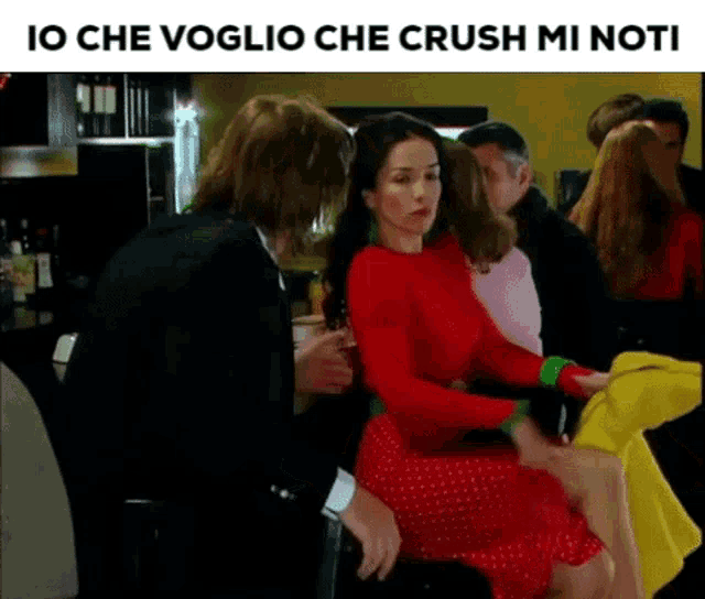 a man in a suit is touching a woman in a red dress in a bar .