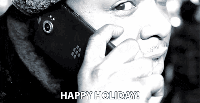 a black and white photo of a man talking on a blackberry phone with the words happy holiday below him
